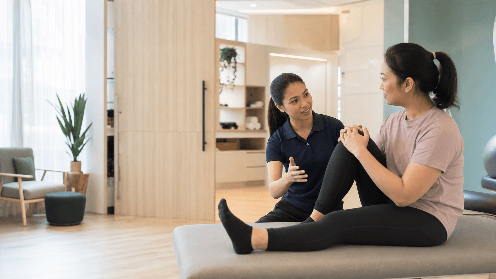 A Malaysian physiotherapy professional speaking with a customer in a welcoming clinic