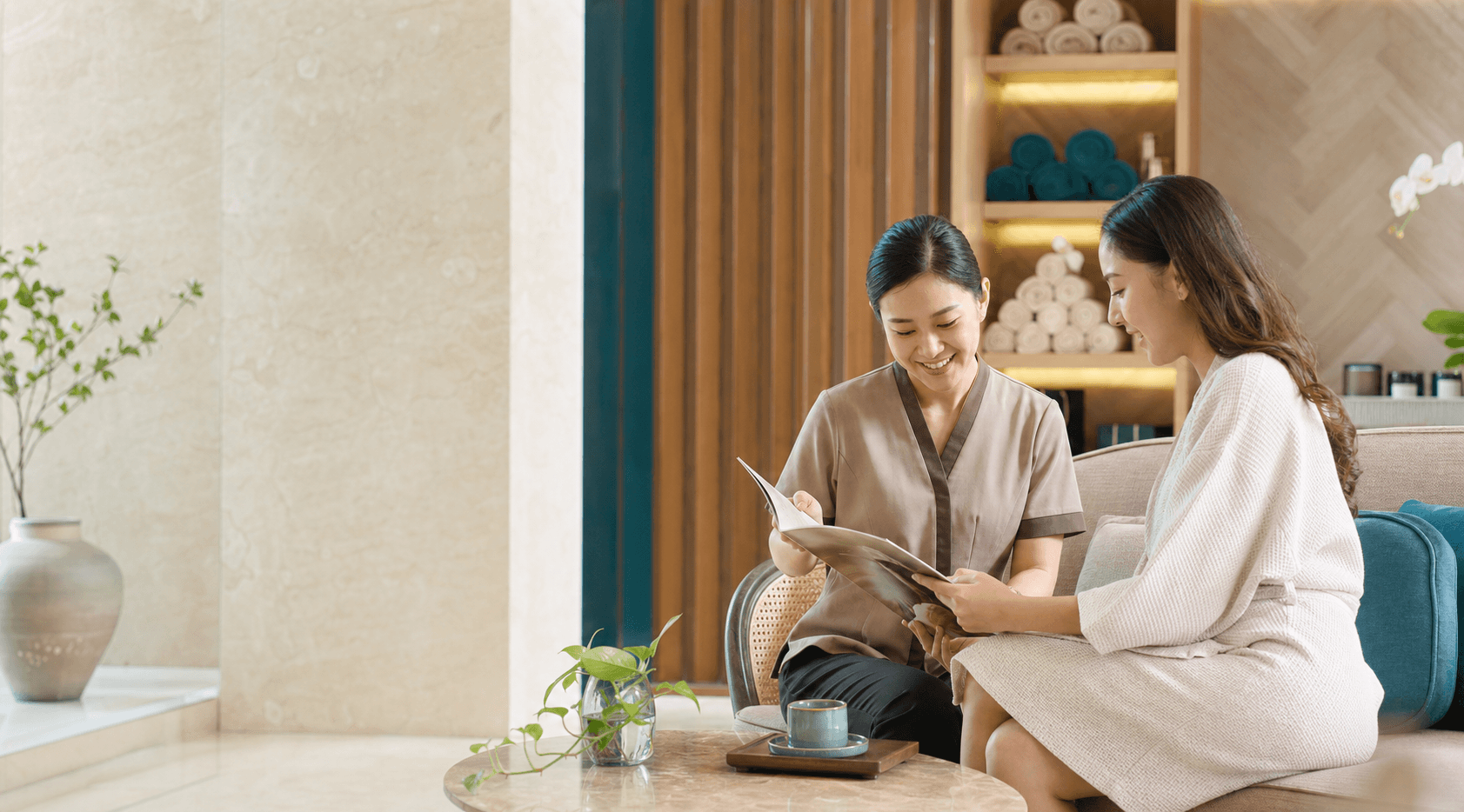 A spa receptionist helping a guest choose a suitable service